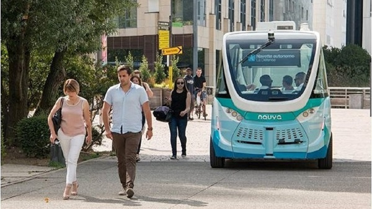 selbstfahrender Bus in einer Stadt neben Fussgängern